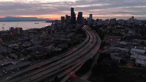 Beautiful-Cityscape-Aerial-with-Pink-and-Orange-Sunset-on-City-by-Ocean-and-Mountains