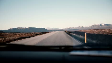 Ve-dentro-del-coche-a-través-del-parabrisas-en-el-camino-de-la-campiña-con-hermosa-puesta-de-sol,-paisaje-de-montaña