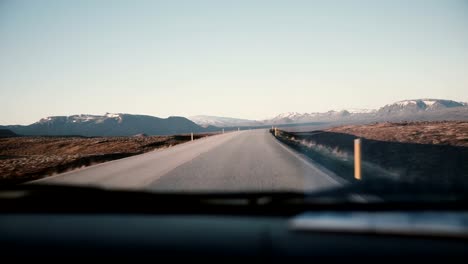 View-inside-the-car-through-the-windshield-on-beautiful-countryside-road-with-beautiful-sunset,-mountains-landscape