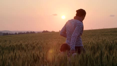 junge-asiatische-Familie-in-einem-Feld-mit-einem-Baby-1-Jahr-auf-der-Hand,-das-Konzept-von-Familienglück,-schöne-Sonne,-Sonnenuntergang,-Slow-motion