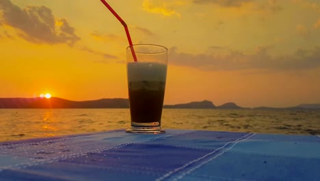 Café-helado-contra-la-hermosa-puesta-de-sol-y-el-mar.