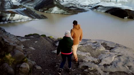 Young-traveling-couple-walking-through-the-mountains,-going-to-see-glaciers-in-Vatnajokull-ice-lagoon-together