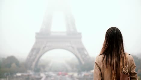 Young-attractive-woman-walking-alone-in-downtown,-exploring-the-Eiffel-tower-on-foggy-morning-in-Paris,-France