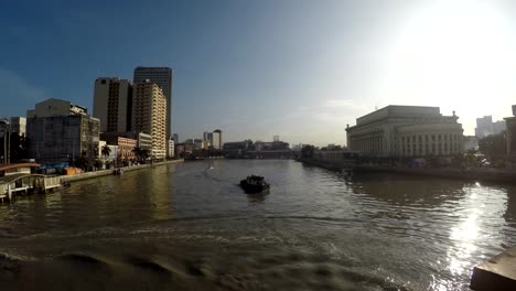 Nave-de-portador-de-la-vela-hacia-el-puente-enorme,-turbio-río-Pasig-temprano-en-la-mañana