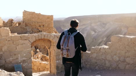 European-man-explores-ancient-mountain-scenery.-Young-male-tourist-with-camera-and-backpack-takes-photos.-Israel-4K