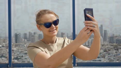 Lächelnde-Frau,-Zelle-Foto-gegen-Tel-Aviv-Blick-aus-der-Höhe