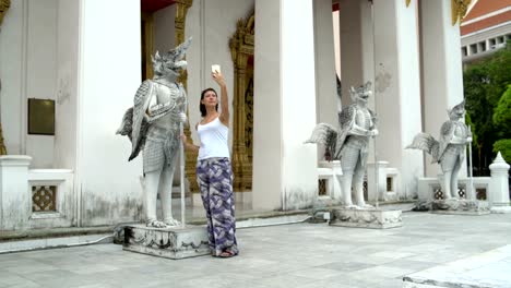 A-woman-makes-selfie-on-a-smartphone-next-to-a-mythological-stone-statue