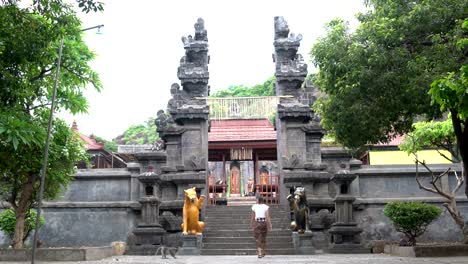 Eine-Frau-in-einem-langen-Rock-steigt-die-Schritte-zu-einem-buddhistischen-Tempel