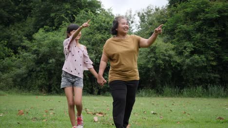 Slow-motion-of-Happy-grandmother-with-granddaughter-playing-in-the-park