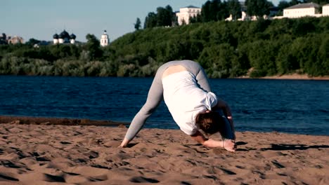 Woman-stretching-yoga-on-the-beach-by-the-river-in-the-city.-Beautiful-view.