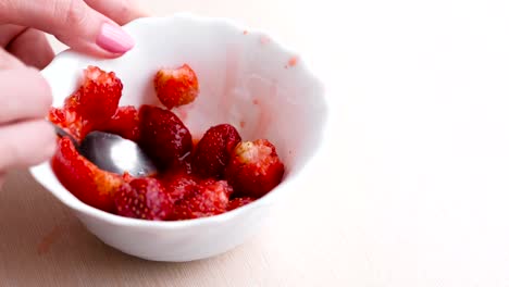 Mujer-amasa-fresas-con-una-cuchara-y-la-mezcla-con-el-azúcar,-hacer-mermelada.-Mano-de-primer-plano.