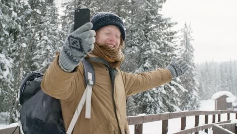 Video-llamada-en-teléfono-inteligente-en-invierno-bosque-joven