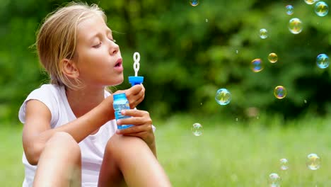 Niña-jugando-con-pompas-de-jabón-al-aire-libre.-Cámara-lenta.