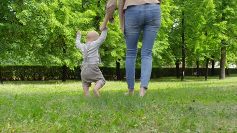 Mother-and-Baby-Boy-Walking-Barefoot-on-Grass