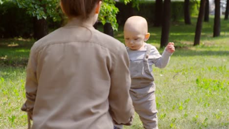 Mutter-beobachten-Baby-Trippeln-im-Park