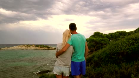 Young-couple,-embracing,-looking-at-the-stormy-sea,-Greece