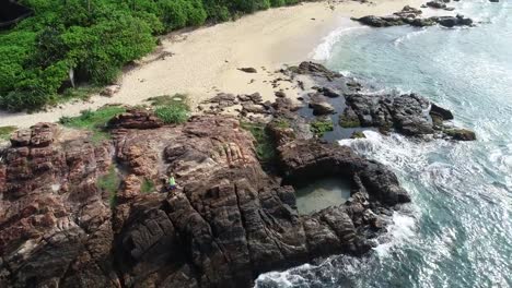 Young-woman-open-arms-on-cliff-edge-at-seaside,aerial-footage