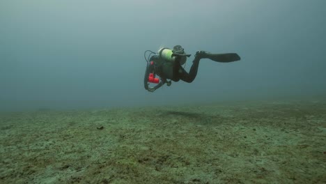 Scuba-diver-floating-on-sea-bottom,-underwater-view.-Deep-sea-diving-concept