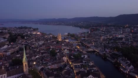 Crepúsculo-iluminado-Zurich-centro-ciudad-orilla-aérea-panorama-4k-Suiza