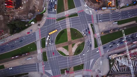 Vista-aérea-de-la-ciudad,-volando-sobre-una-ciudad,-un-sugerente-video-aéreo-perpendicular-sobre-una-rotonda-de-tráfico-con-mucho-tráfico