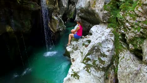 AERIAL:-Young-woman-watching-a-waterfall-in-beautiful-rocky-canyon
