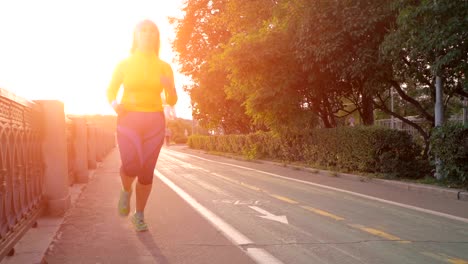 female-runner-running-at-sunset-in-city-park.