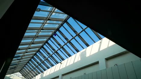 Glass-ceiling-of-the-shopping-center-with-paper-garlands-on-a-background-of-time-lapse-light-of-the-sun-rays-on-a-blue-sky