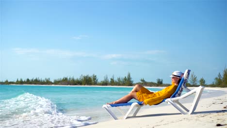 Junge-Frau-entspannen-im-Liegestuhl-an-einem-tropischen-Strand