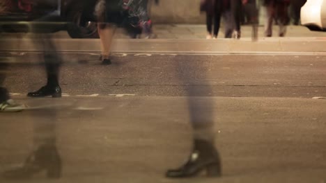 Pedestrians-crossing-a-road-at-night,-London,-England