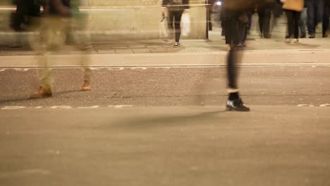 Pedestrians-crossing-a-road-at-night,-London,-England