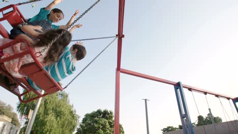 Niños-que-hace-pivotar-juntos-en-un-parque-infantil-público