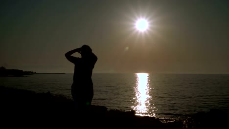 Girl-straightens-hair-on-the-beach-at-sunset.