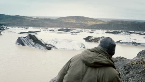 Joven-guapo-de-senderismo-en-las-montañas-cerca-de-la-laguna-de-hielo-Vatnajokull,-buscando-en-los-glaciares-en-Islandia