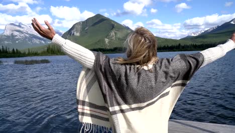 Mujer-joven-de-pie-junto-al-lago-abrazando-la-naturaleza-con-sus-abiertos-brazos