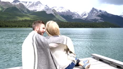 Couple-relaxing-on-lake-pier-in-Springtime,-Jasper-national-park,-Canada