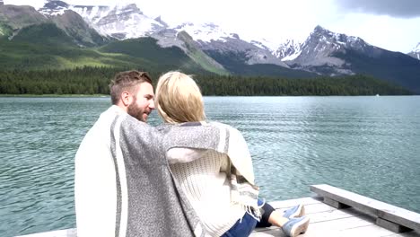 Pareja-relajante-en-muelle-de-lago-en-la-primavera,-el-Parque-Nacional-Jasper,-Canadá