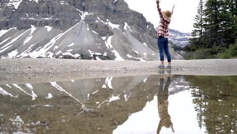 Junge-Frau-steht-von-einer-wunderschönen-Bergkulisse-See-mit-ihre-Arme-weit-offen