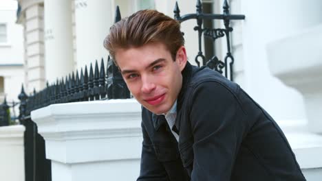 Portrait-Of-Stylish-Young-Man-Sitting-On-Steps-Of-City-Building