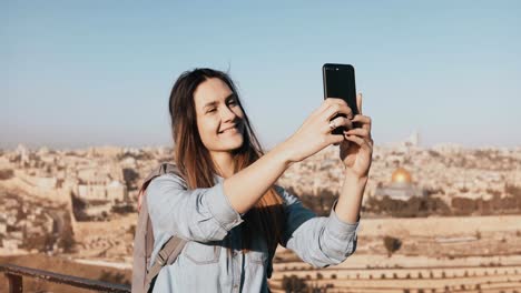 Pretty-girl-takes-selfie-in-Jerusalem-old-town.-Cute-local-girl-smiles-happy,-taking-photos.-Ancient-Israel-panorama-4K