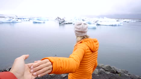 Follow-me-to-concept,-young-woman-leading-boyfriend-to-glacier-lagoon-in-Iceland