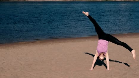 Woman-doing-yoga-on-the-beach-by-the-river-in-the-city.-Beautiful-view.-Gymnastics-wheel