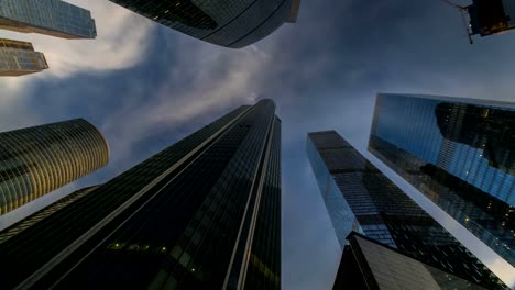 Bottom-up-Blick-auf-rotierende-Wolkenkratzer-und-fliegenden-Wolken,-Zeitraffer,-hyper-Zeitraffer