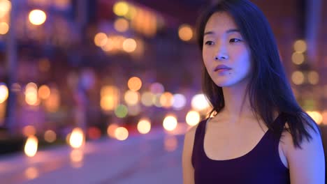 Happy-Asian-Woman-Thinking-Outdoors-At-Night