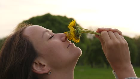 Mujer-disfruta-el-aroma-de-flores-de-diente-de-León