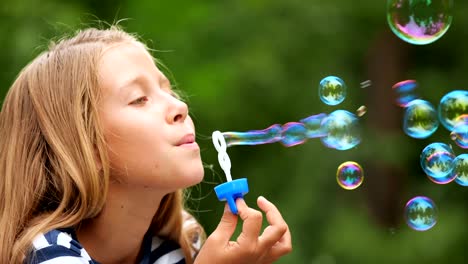 Niña-jugando-con-pompas-de-jabón-al-aire-libre.-Cámara-lenta.