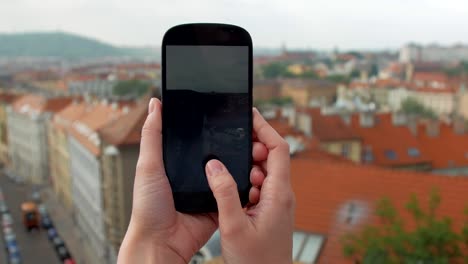 weibliche-Hände-halten-Smartphone-und-die-Fotos-von-Panorama-von-Prag