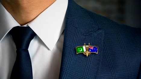 Businessman-Walking-Towards-Camera-With-Friend-Country-Flags-Pin-Pakistan---Australia