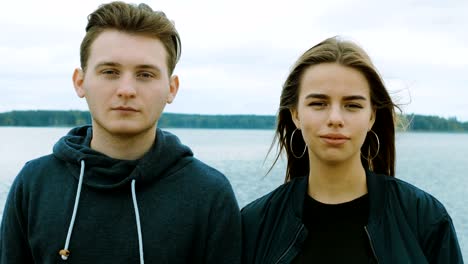Portrait-of-two-teenagers,-a-guy-and-a-girl,-against-the-background-of-a-river-and-forest.