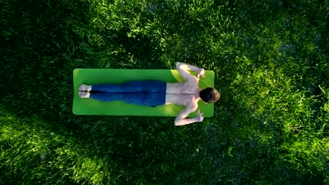 Brunette-guy-doing-yoga-moves-on-green-grass