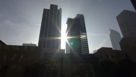 Sun-rays-shine-between-skyscrapers-in-downtown-Los-Angeles--street-dolly-shot